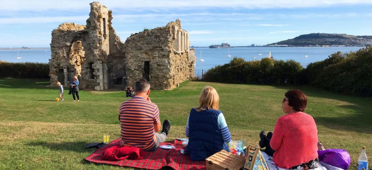 Three people having a picnic at Sandsfoot Castle, Weymouth, Dorset