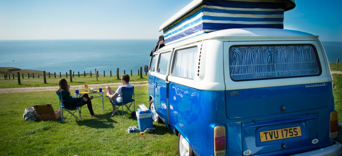 A man and woman enjoying the view of the Jurassic Coast from their campervan