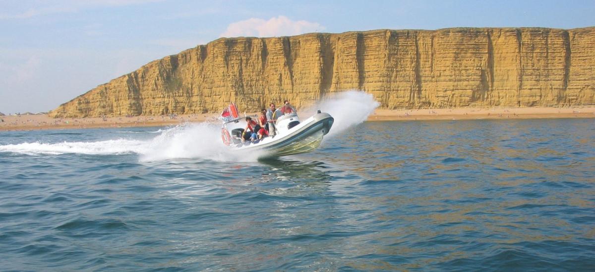 Lyme Bay RIB Charter boat passing East Cliff at West Bay in Dorset