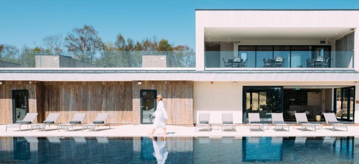 Woman in robe walking next to swimming pool at Silverlake Dorset