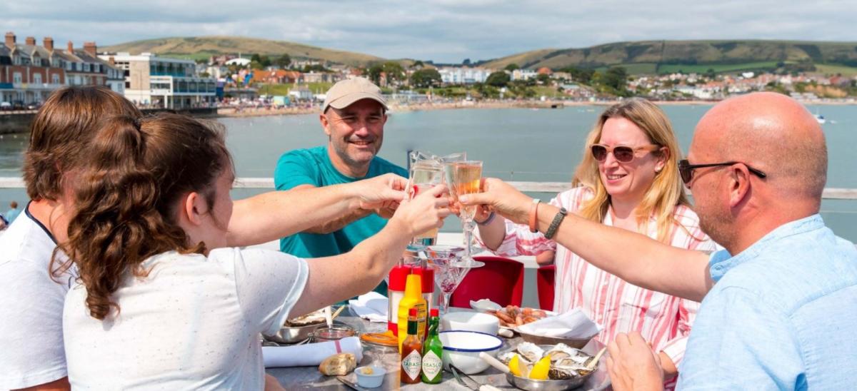 Five people enjoying food and drinks overlooking Swanage Bay in Dorset