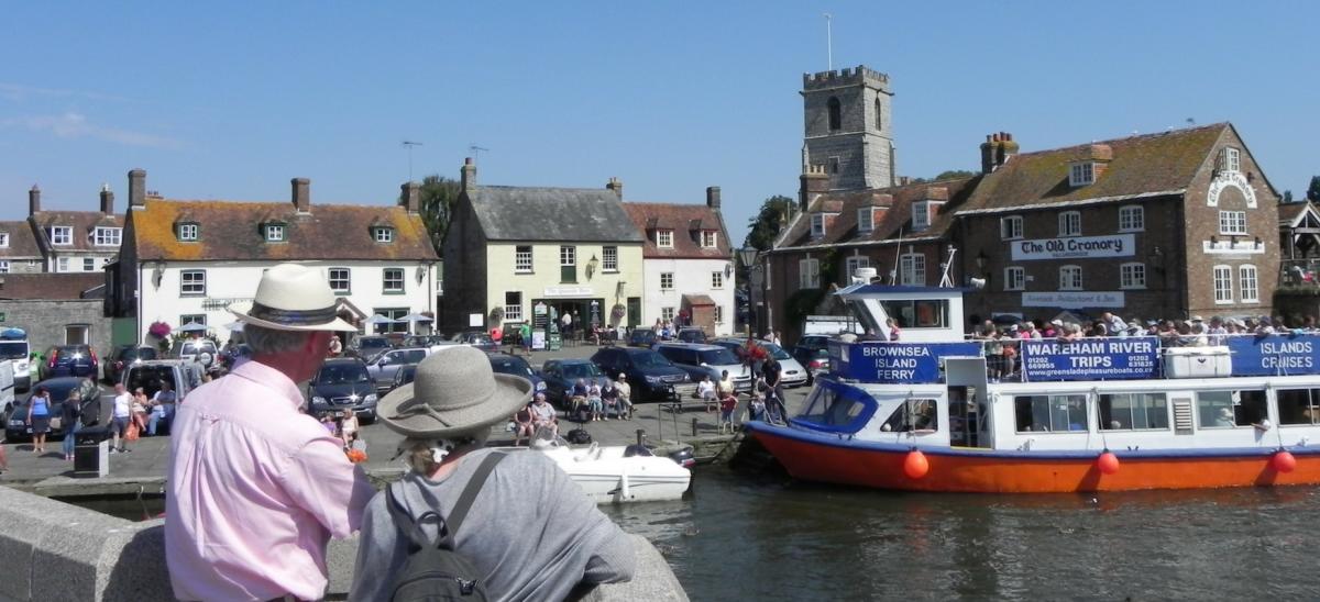 Man and woman standing on South Bridge looking at the boats on Wareham Quay, Dorset