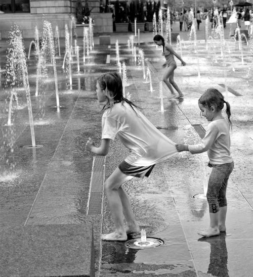 Black and white photo of three girls playing in fountain