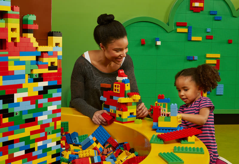 Mother and young daughter build with Lego's at the play station