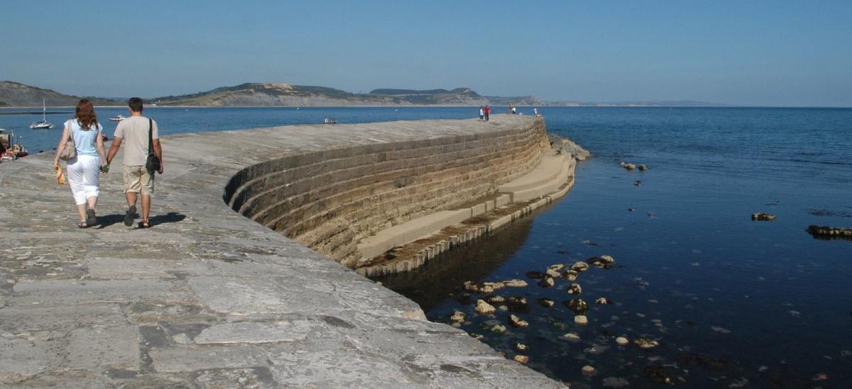 Couple walking along The Cobb, Lyme Regis in Dorset