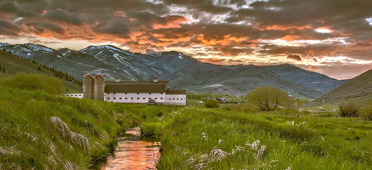 Scenic of a White Barn during a colorful Spring Sunset with mountains in the background