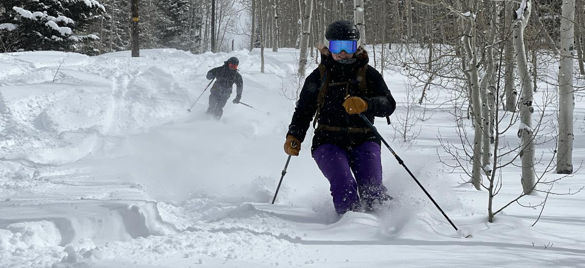 Two skiers make turns in powder snow on a ski run near Park City, UT