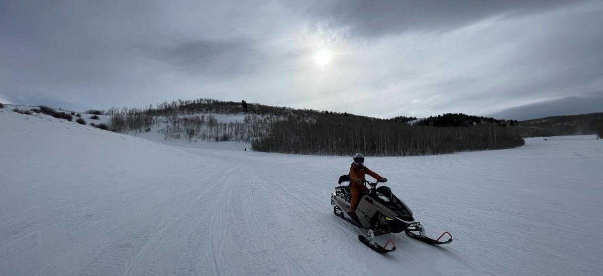 Person riding a snowmobile in a vast landscape of snow.