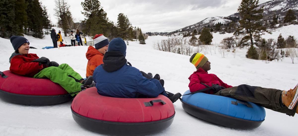four teenagers tubing down a hill
