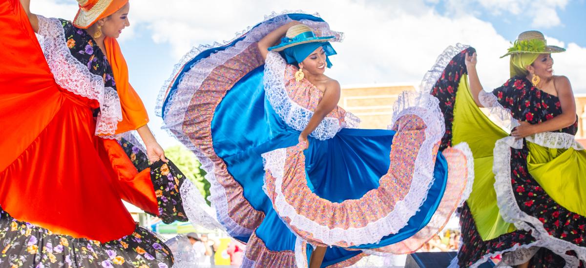 Three women dancing in elaborate dresses.