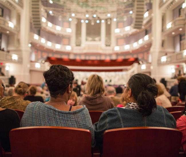 Row of people sitting in spacious Palladium Theater ready for performance to begin