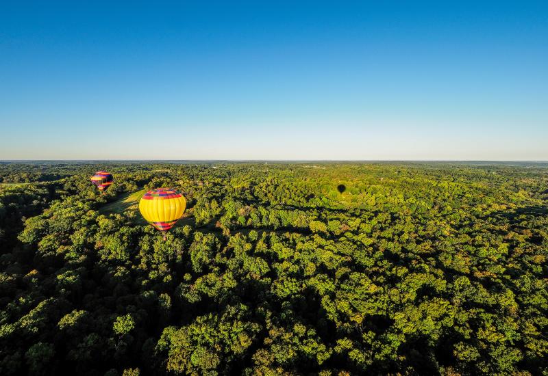 Two hot air balloons floating over the rolling hills of Monroe County
