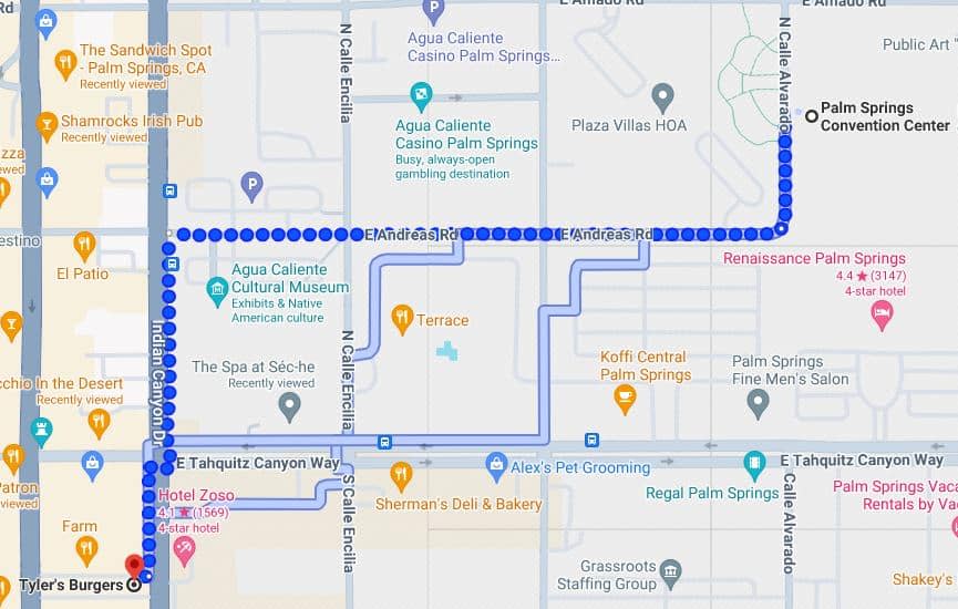 Screenshot of a digital map featuring part of Palm Springs, California, with points of interest marked, including hotels, restaurants, a casino, and a cultural museum. A dotted line indicates a travel route along E Andreas Rd.