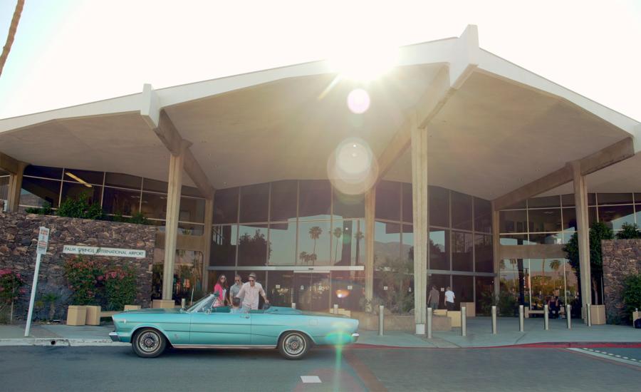 Three people in vintage car in front of PSP.