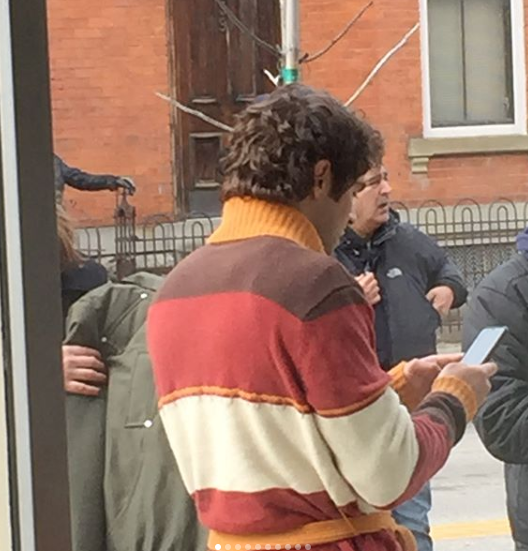 Image is of the back and side view of Zac Efron dressed as Ted Bundy in Mainstrasse.