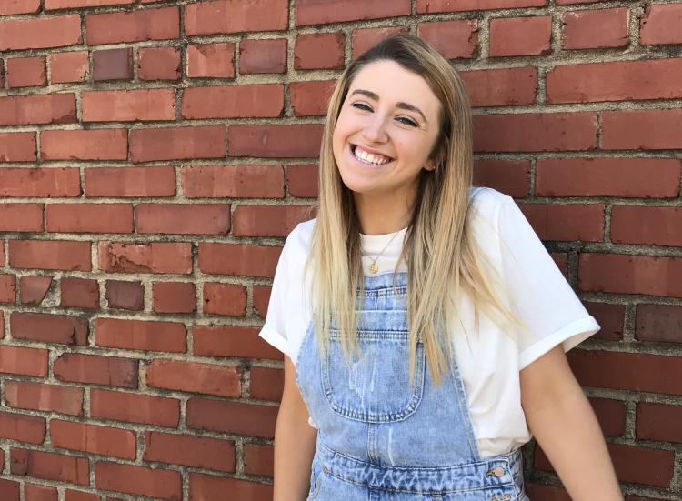 Rebekah Gregg poses for a photo against a brick backdrop