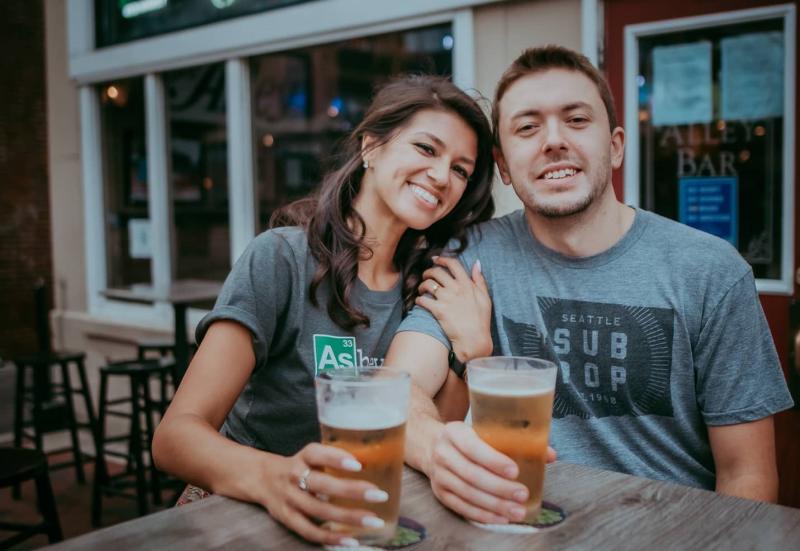 A couple smiling at the camera on Alley Bar's patio