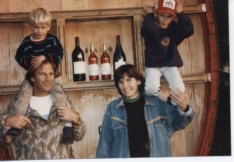 The Udsen family stands with children in front of large barrel.