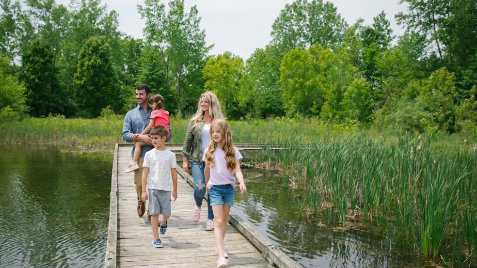 Family of five walking a boardwalk over a marsh at the M.L. Red Trabue Nature Preserve