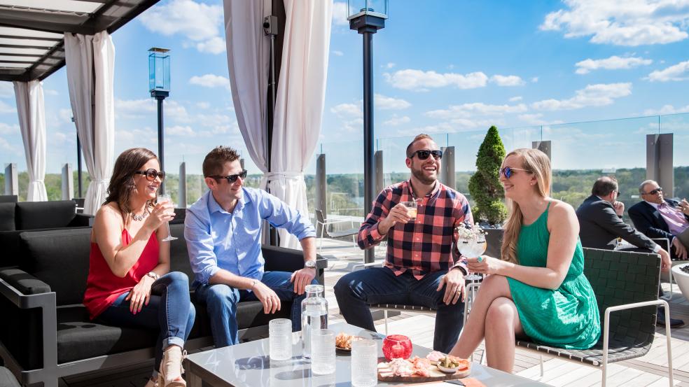 Two couples enjoying cocktails on the rooftop patio at VASO