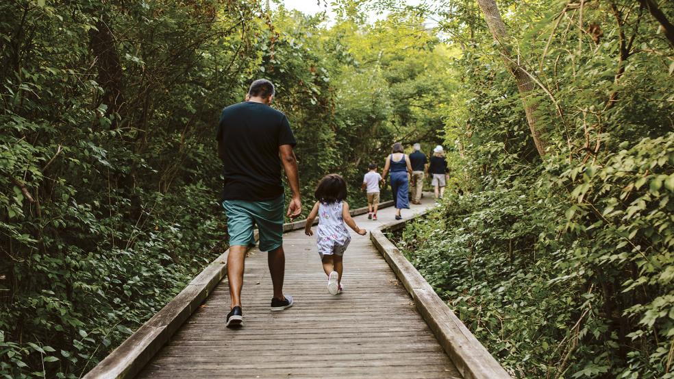 A family running down the boardwalk at Kiwanis Riverway Park