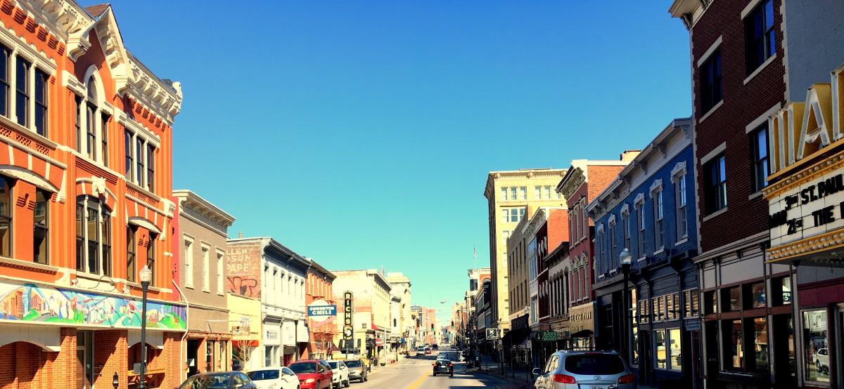 Image of Madison Ave during the day with cars on the street and the buildings on both sides.