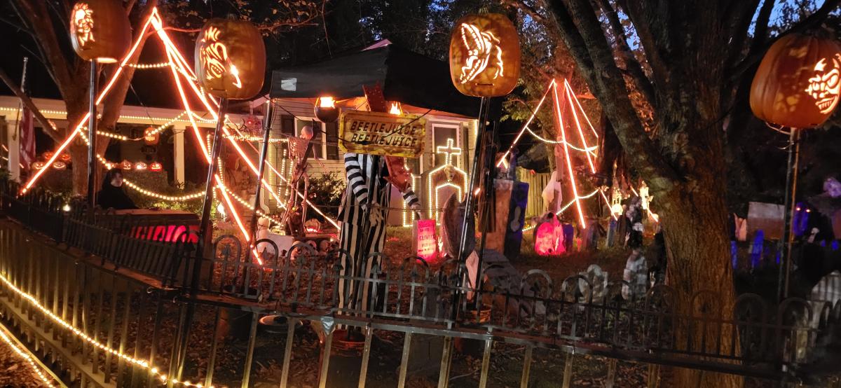 Home display of Halloween decorations including lighted pumpkins, tombstones, spider lights, Beetlejuice, and more