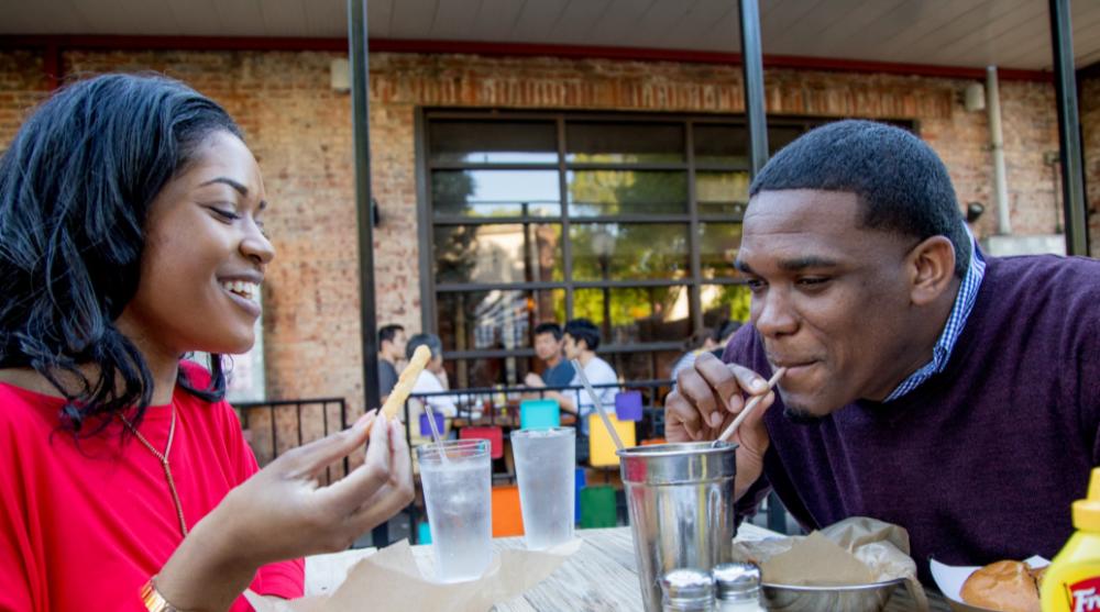 Smiling couple enjoying food and drink in an outdoor patio in Athens, GA