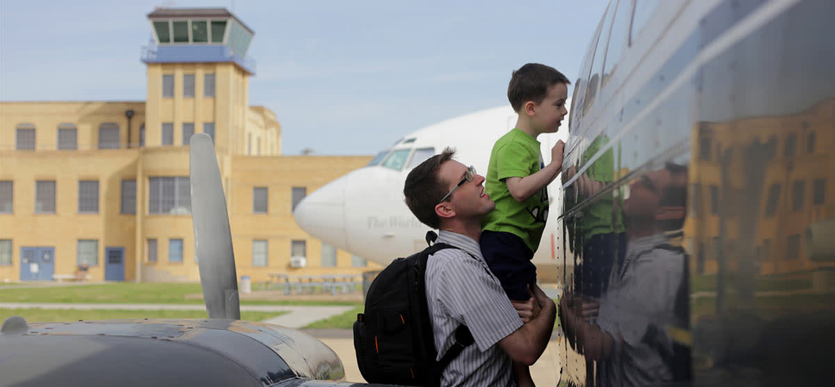 A young father lifts up his son to get a closer look at an airplane at the Kansas Aviation Museum