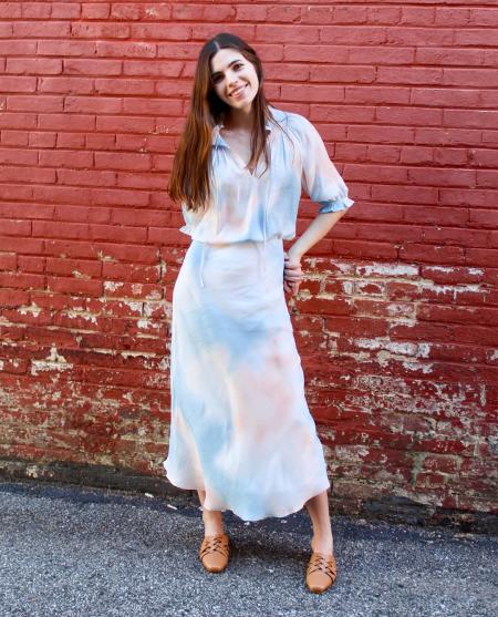 A dark haired girl wears a blue and pink tie dye dress.