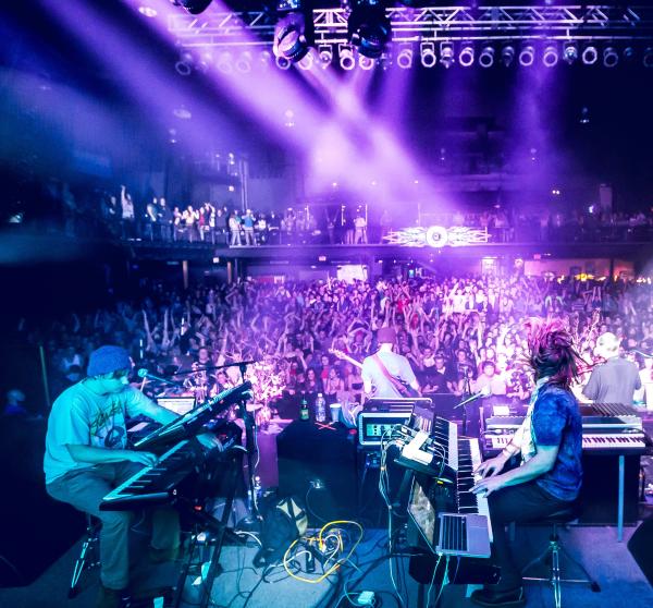 View from stage at Newport Music Hall of live band playing for large crowd under vibrant lights