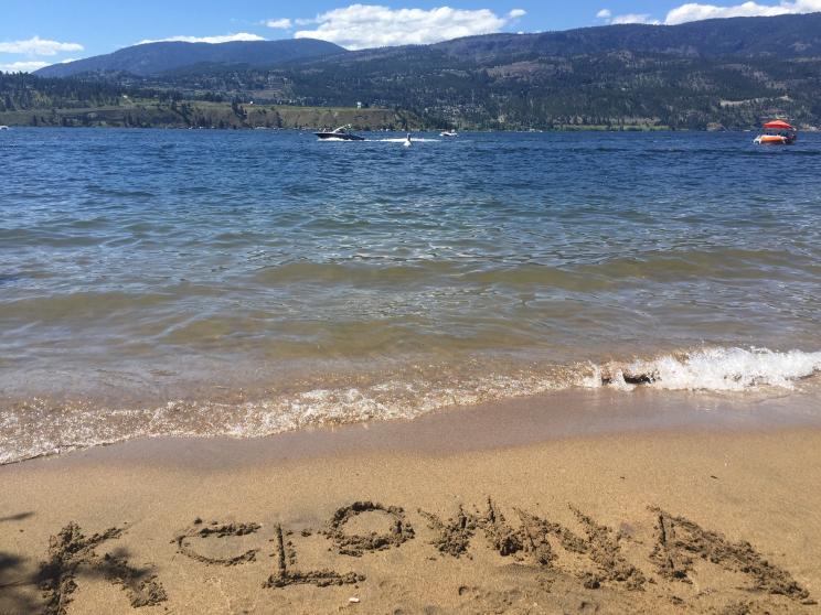 "Kelowna" written in the sand on the shores of Okanagan Lake