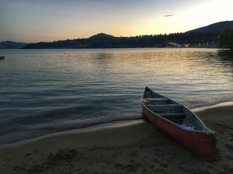 Canoe perched ashore while the sun sets on Okanagan Lake