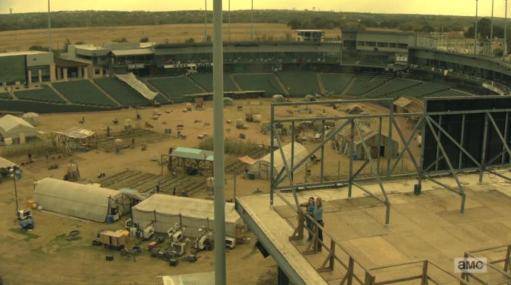 Fear the Walking Dead screengrab looking down at a ballpark diamond from the sky. The field area is being used as an encampment with tents and greenhouses