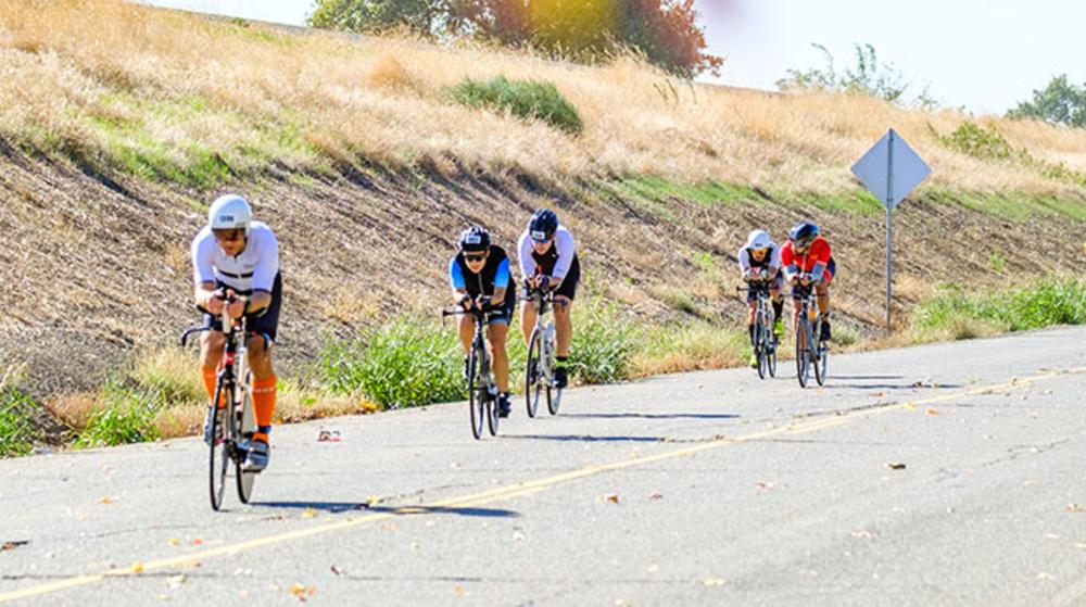 cyclists biking next to the levee of the river