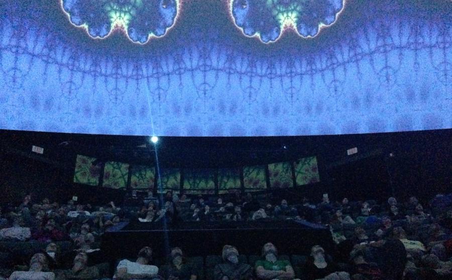 People sit inside a planetarium watching a presentation on fractals