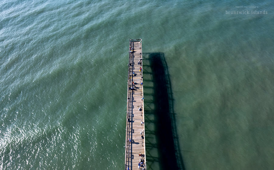 an aerial above view of a wooden pier extending into the ocean