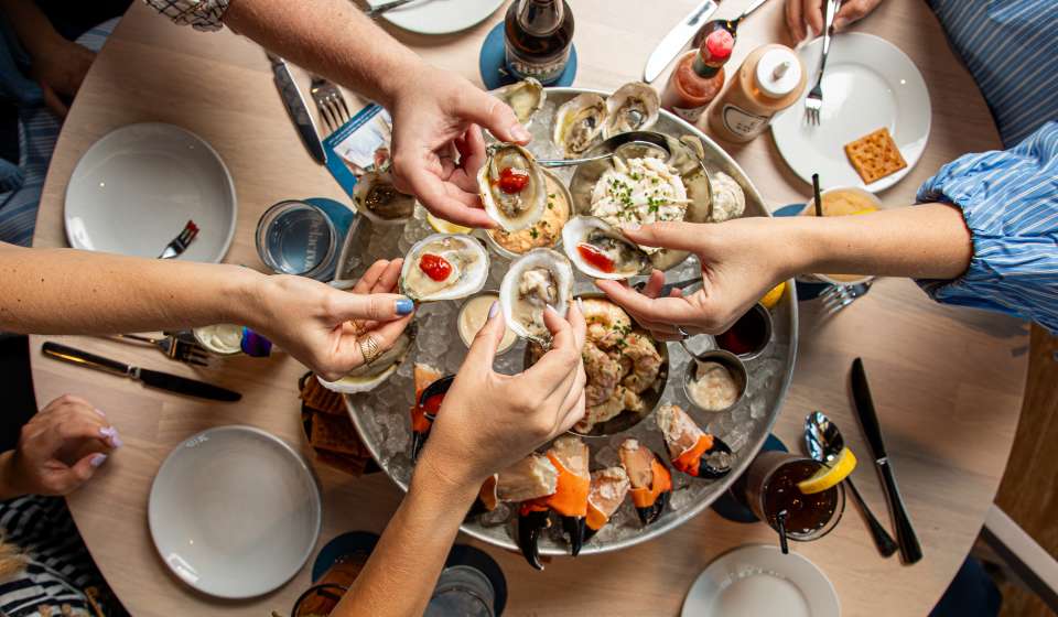 Friends share raw oysters, crab, and other chilled seafood as part of the seafood Plateau at Delacroix