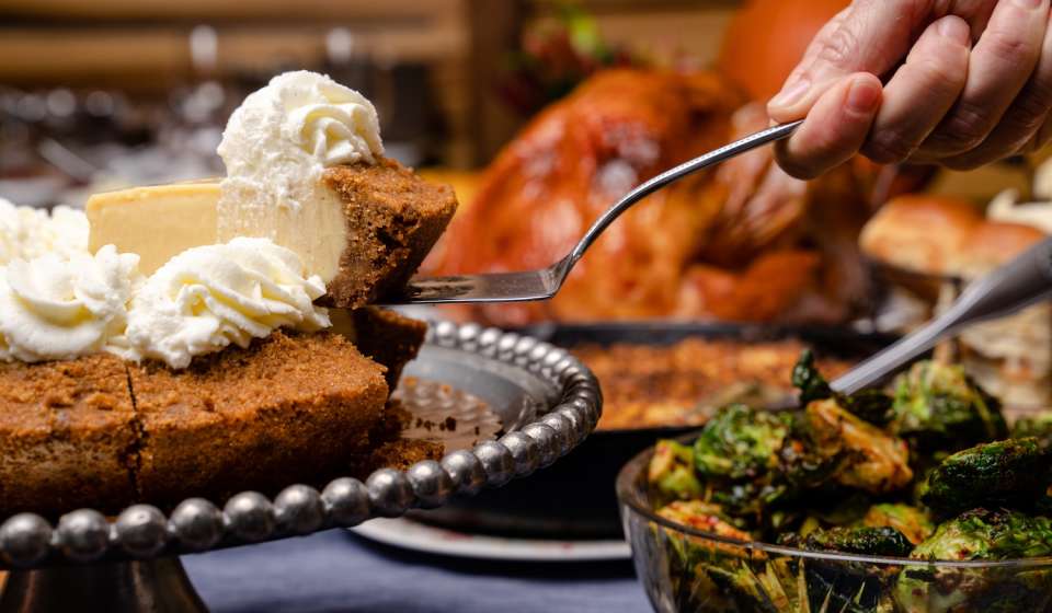 A slice of pie being taken from a Thanksgiving feast