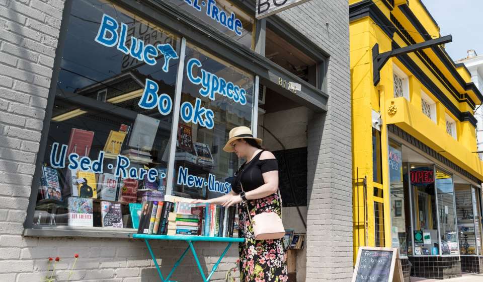 a woman browses the selection of books outside of Blue Cypress Books on Oak Street