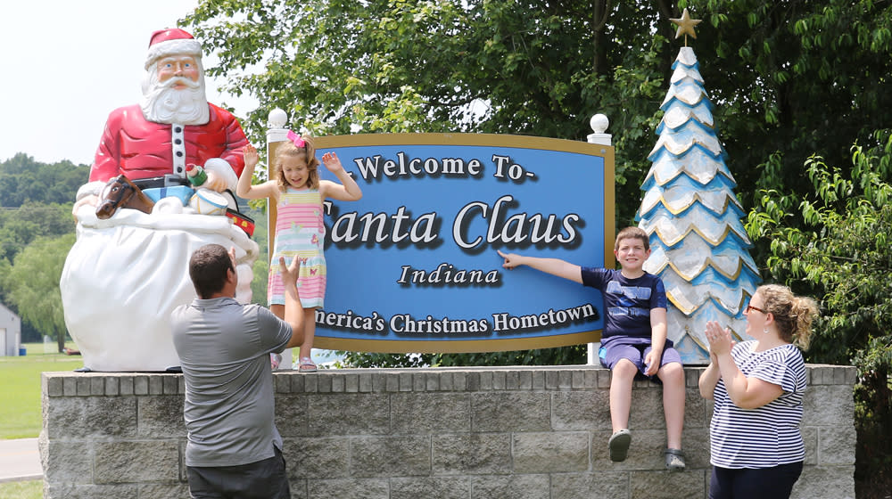 Family taking a photo in front of the Santa Claus's Welcome Sign