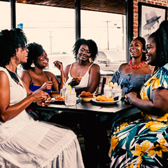 group of black women enjoying a meal at a restaurant