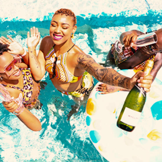 group of black women enjoying cocktails in a swimming pool