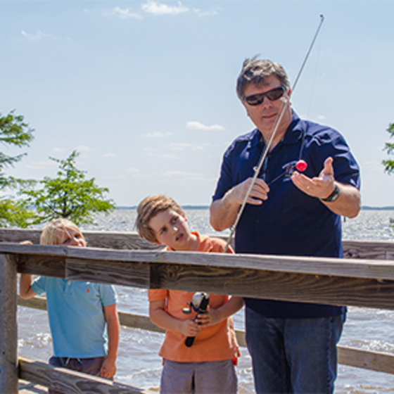 Man and grandsons fishing from lake pier at Caddo Lake