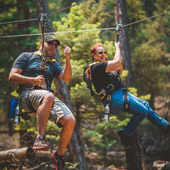 Couple ziplining on parallel racing spans
