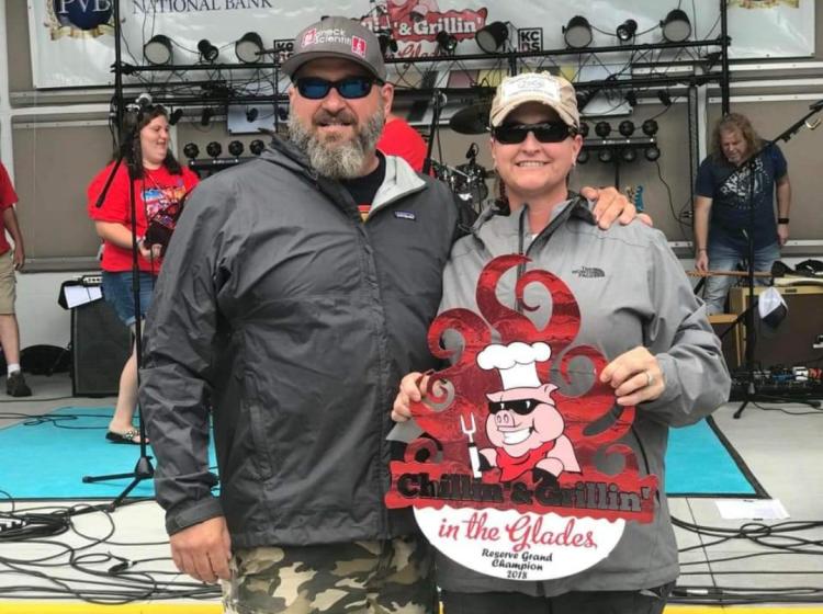 Roxanne and Jerry stand with bbq comp trophy