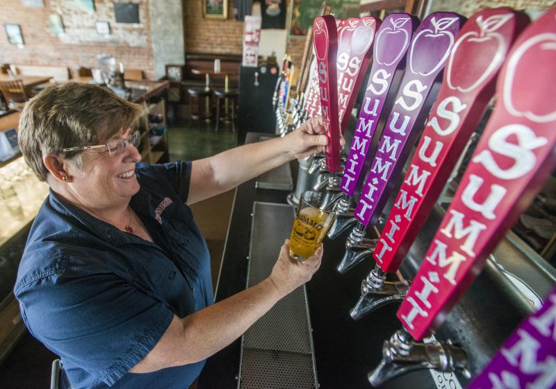 a photo of a lady pouring a hard cider