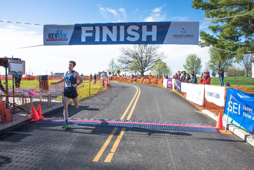 First-place winner Trevor van Ackeren of Bethlehem blasts across the finish line to complete the 2017 Valley Forge Revolutionary 5-Mile Run®. He completed the course in 25:28.