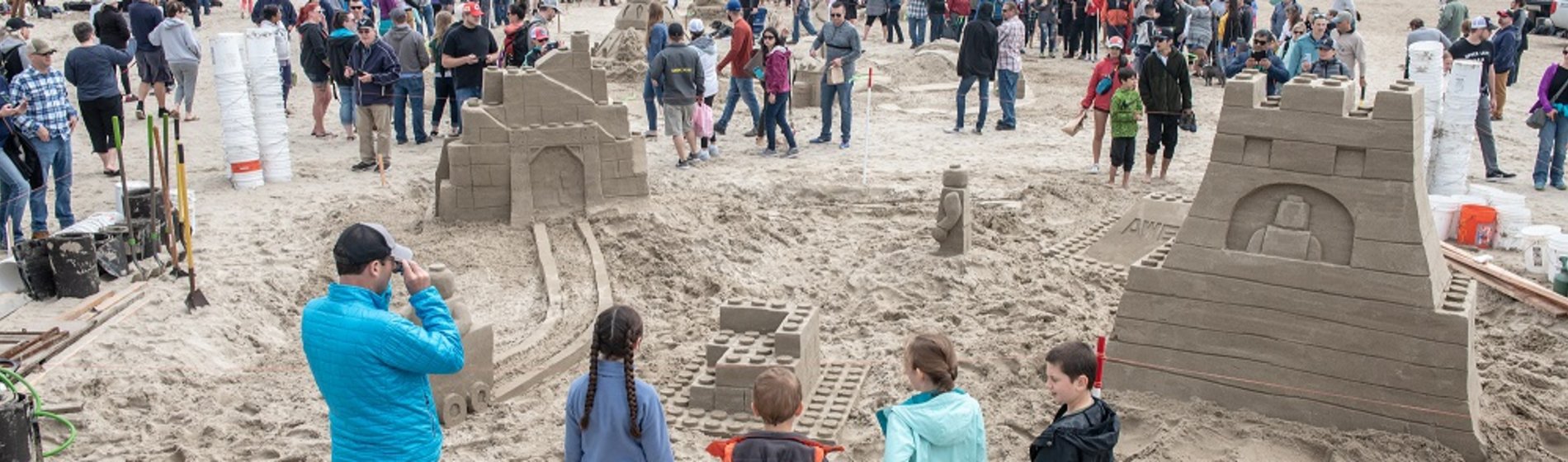 A crowd admires two sandcastles at the annual Sandcastle Contest.
