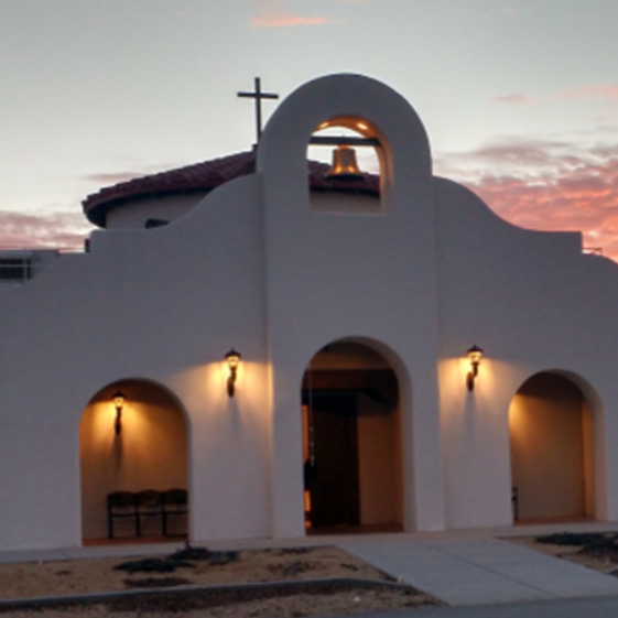 Stucco church building with arched entryways and a bell tower silhouetted against a sunset sky.
